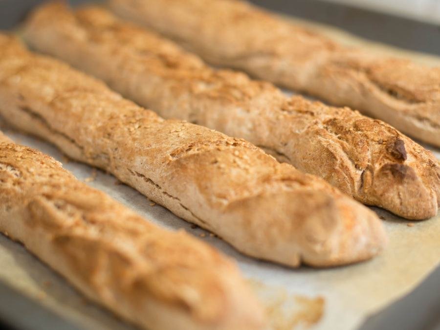 Golden seeded baguettes on a baking tray