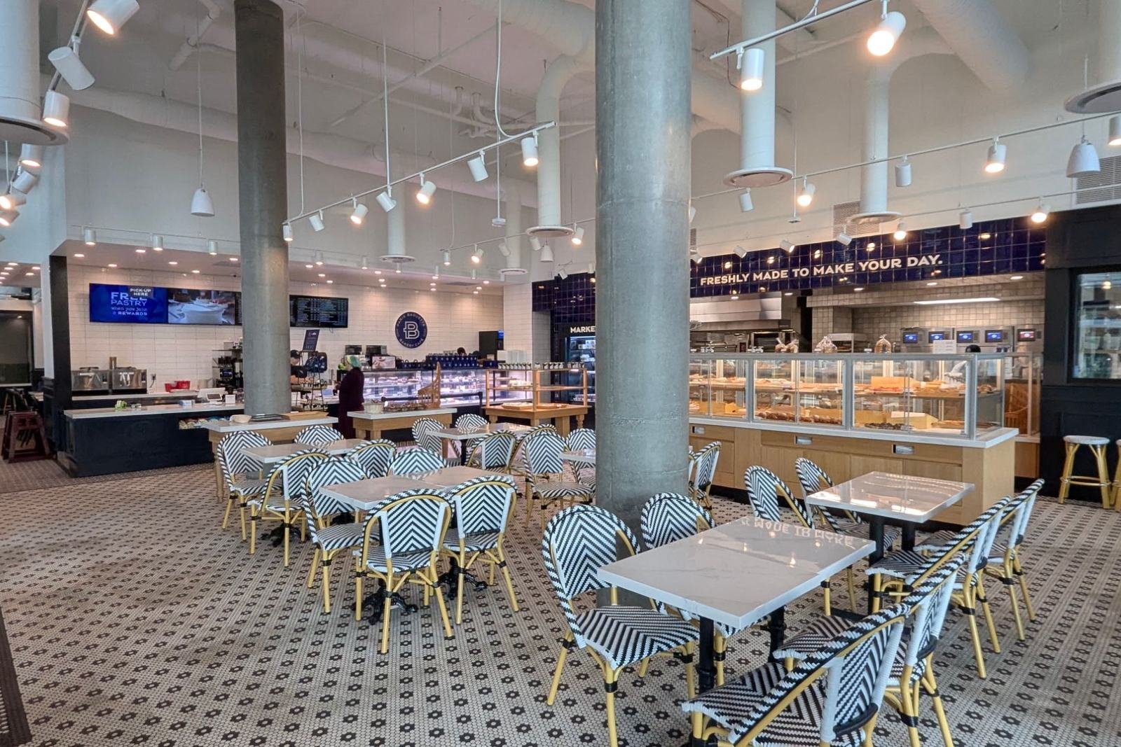 A bright café dining room with marble tables and woven bistro chairs