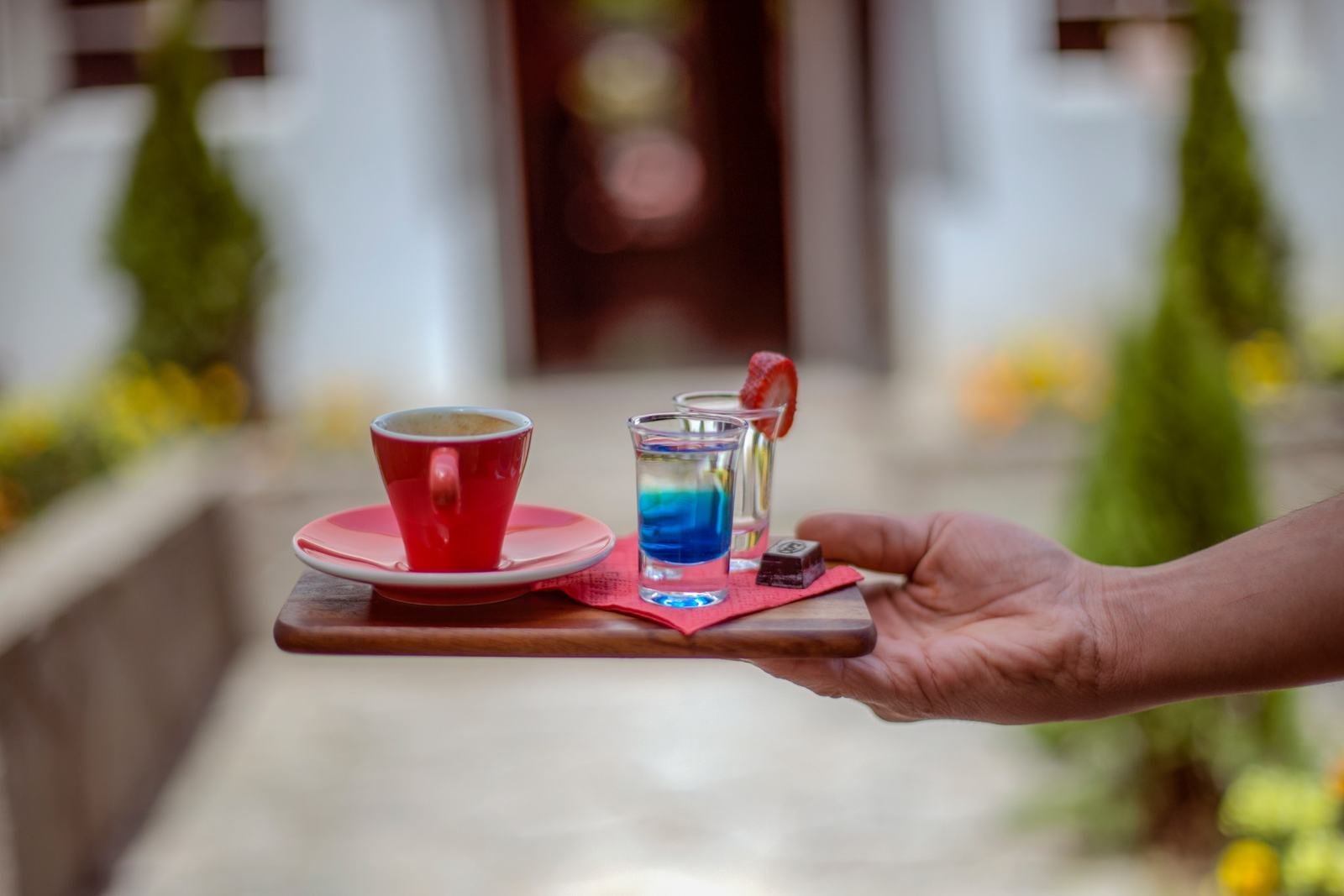 An espresso served on a wooden tray with a sweet on the side